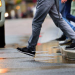 Man stepping over puddle in rain