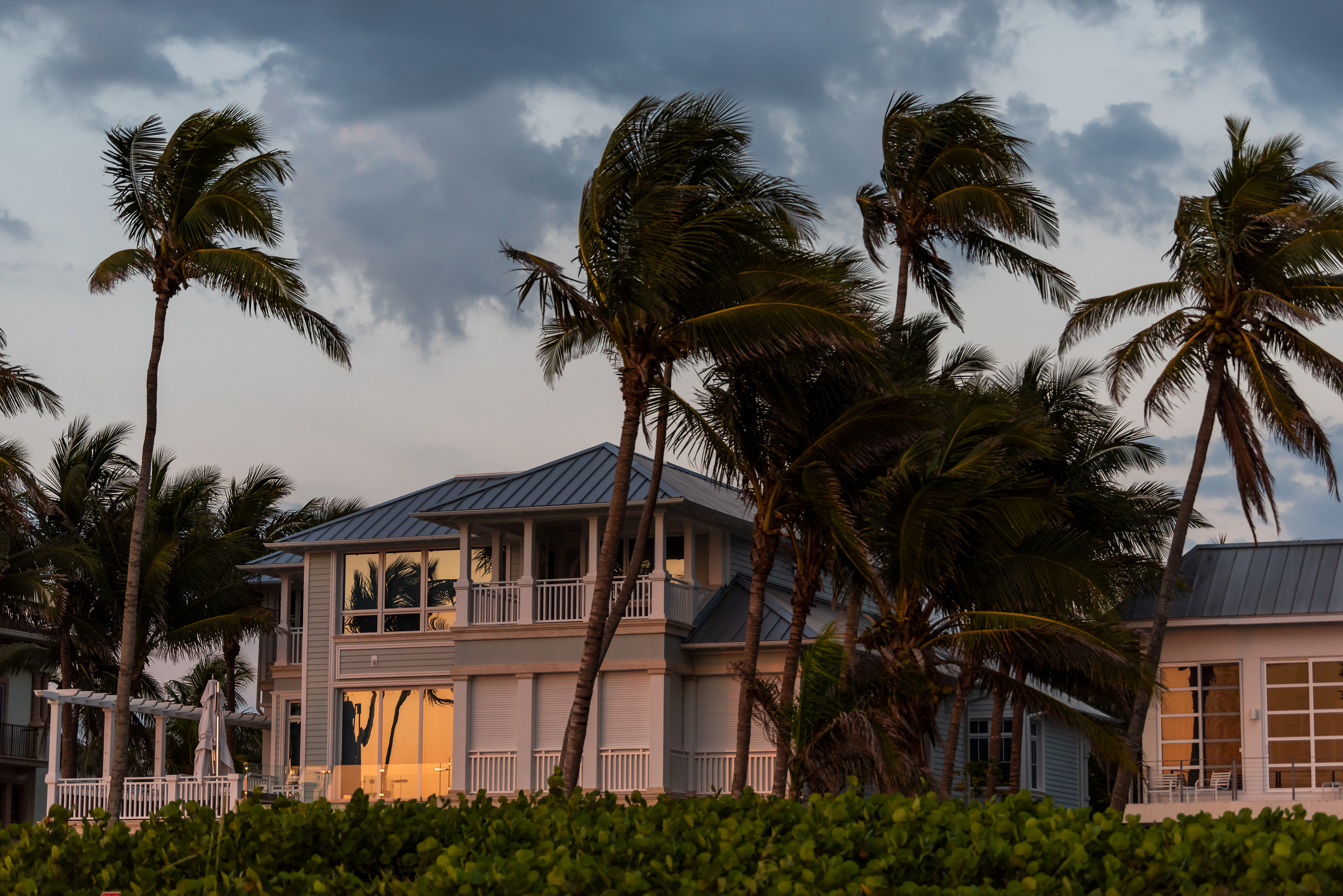 Florida coast beachfront home wit palm trees during evening sunset with stormy weather approaching