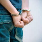 Man arrested with handcuffs around his wrists.