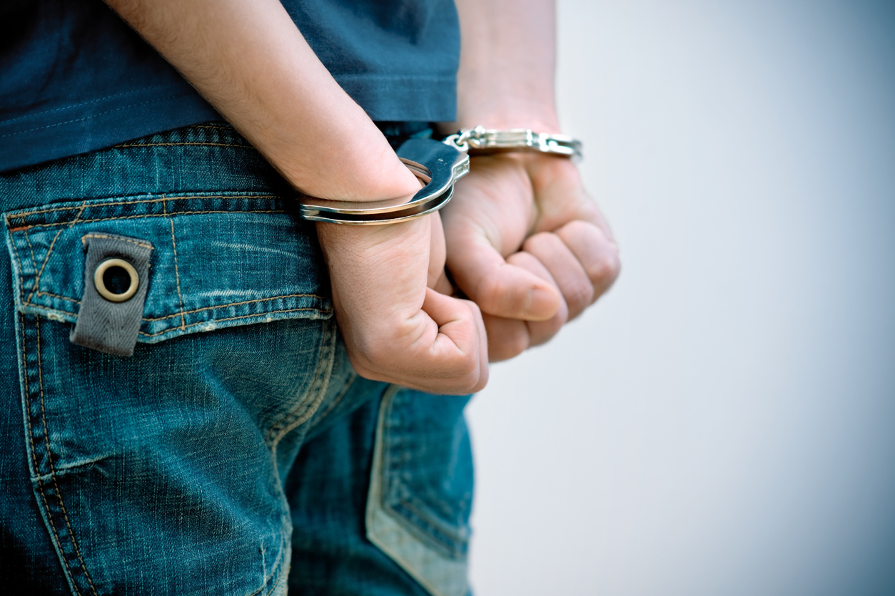Man arrested with handcuffs around his wrists.