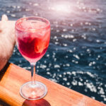 Pink cocktail on the edge of a boat rail